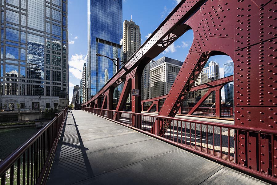 About Our Agency - A Red Steel Bridge in Chicago, Illinois, Spanning the River, High Rises on the Opposite Shore
