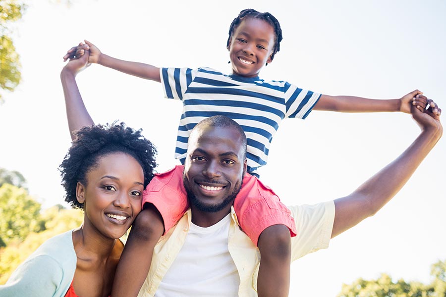 Personal Insurance - Mother and Father and a Young Child on Dad's Shoulders, Smiling and Dressed for Summer